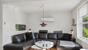 A modern living room with a black leather sectional sofa, a white coffee table, and a pendant light. - Amazing home in Rudkøbing with WiFi (Rudkøbing)