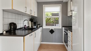 Eine kleine Küche mit Fenster, weißen Schränken, einer schwarzen Arbeitsplatte und Holzboden.