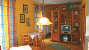 Une pièce confortable comprenant un lit, une table à manger, des chaises, un téléviseur et un buffet en bois doté de portes en verre.