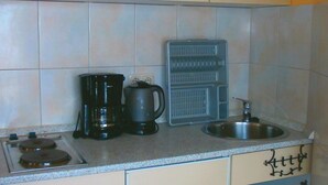 Une cuisine équipée d’une cuisinière à gaz, d’une machine à café, d’une bouilloire et d’un évier.