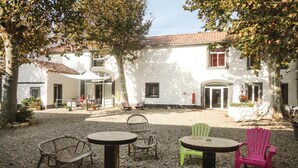 Un patio con mobiliario exterior, incluyendo una mesa y sillas, rodeado de edificios blancos con tejado de baldosas.