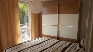 Un dormitorio con cama, armario y ventana con cortinas.