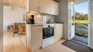 Een moderne keuken met witte kastjes, een inbouwoven en een koffiezetapparaat.