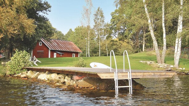 Une jetée s’avançant dans un lac, avec une grange rouge en arrière-plan.