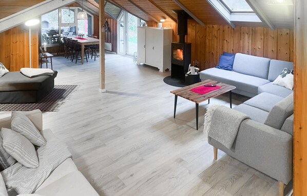 Un espace de vie chaleureux et ouvert, comprenant un coin salon avec cheminée, une table à manger et des sièges confortables.