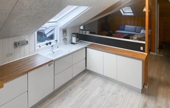 A compact kitchen with a skylight, white cabinets, and a wooden countertop. - Nice home in Thyholm with kitchen (Thyholm)