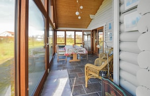 A cozy log cabin with a dining area, wicker chairs, and a view of the surrounding landscape. - Cozy home in Vinderup with sauna (Vinderup)