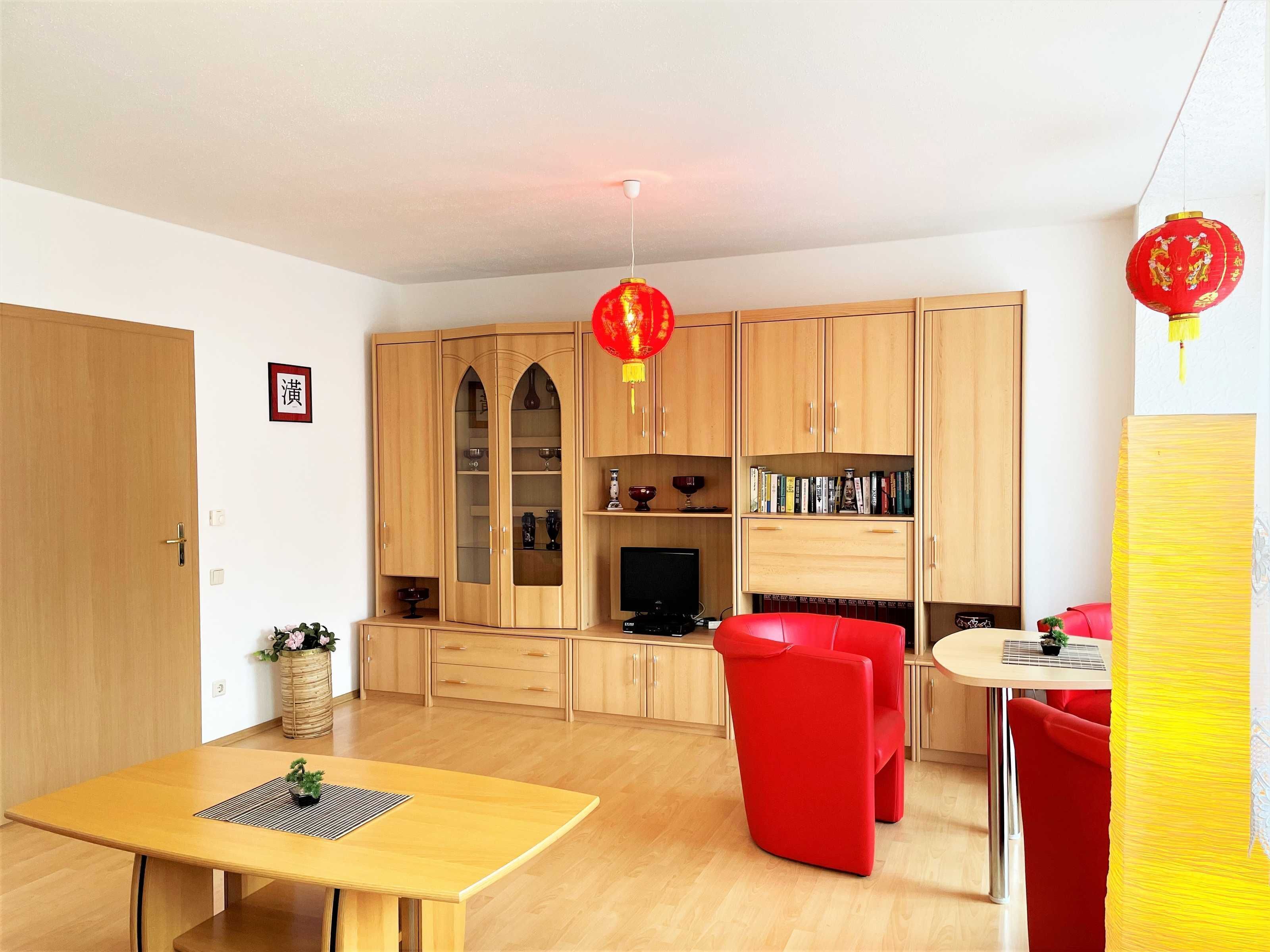 A modern living room with a wooden cabinet, a red sofa, and a dining table.