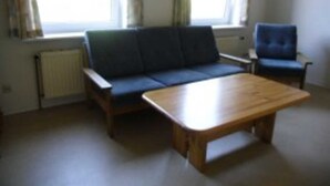 A living room with a sofa, a chair, and a wooden coffee table. - Apartment 1 - Budach: Country vacation at the gates of Flensburg (Handewitt)