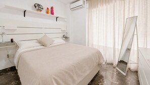 Une chambre d’hôtel équipée d’un lit, d’une table de chevet, d’une lampe, d’un climatiseur et d’un grand miroir.
