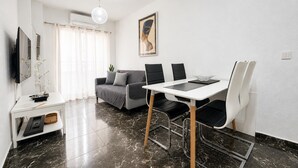 Un salon moderne comprenant un coin repas, un canapé, un téléviseur et un tableau accroché au mur.