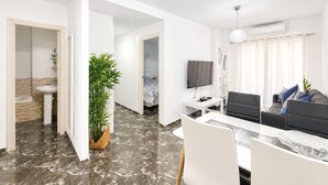 Un salon moderne avec un téléviseur à écran plat, un canapé, une table à manger et une plante en pot.