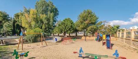 A playground with swings, a seesaw, and a slide.