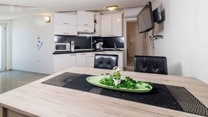Una cuina moderna amb armaris blancs, tauleig negre i zona de menjador amb taula de fusta i dues cadires.