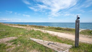 A coastal path with a wooden post and binoculars, leading to the sea.