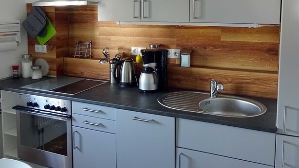A modern kitchen with stainless steel appliances, a wooden backsplash, and a built-in sink.