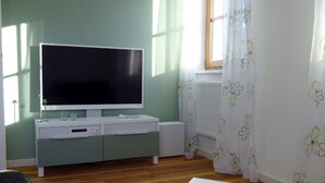 A living room with a flat-screen TV, a white entertainment unit, a fur rug, and a white coffee table.