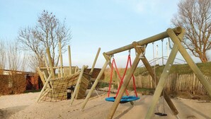 Un parque infantil con columpios y una estructura para escalar.