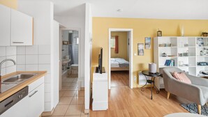 Un espacio habitable compacto con kitchenette, cama, una mesita y sofá.