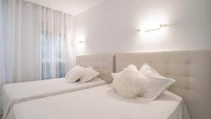 Une chambre d’hôtel avec deux lits, chacun doté d’une tête de lit capitonnée et de linge de lit blanc.