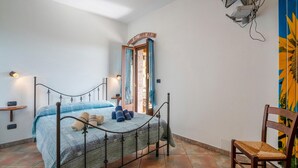 A bedroom with a bed, a chair, a small table, a mirror, and a window with curtains. - 3 bedroom cozy home in Marsaglia CN (Marsaglia CN)