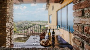 A balcony with a view of the countryside, a table with wine bottles, glasses, and bread. - 3 bedroom cozy home in Marsaglia CN (Marsaglia CN)