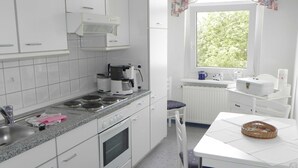 Uma cozinha moderna com armários brancos, fogão e área de jantar com mesa e cadeiras.