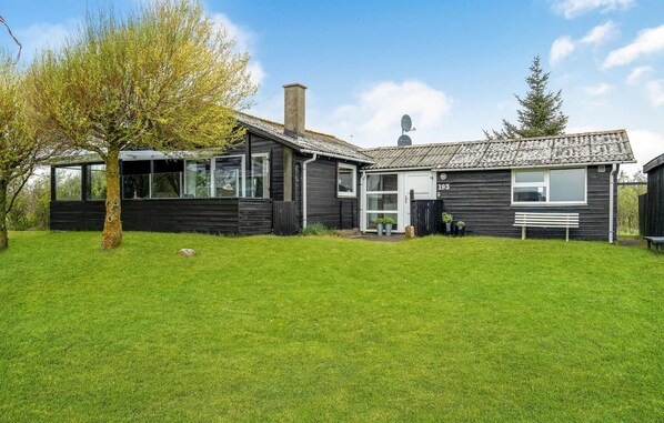 Een modern herenhuis met twee verdiepingen, een donkere gevel, grote ramen en een verzorgd gazon.