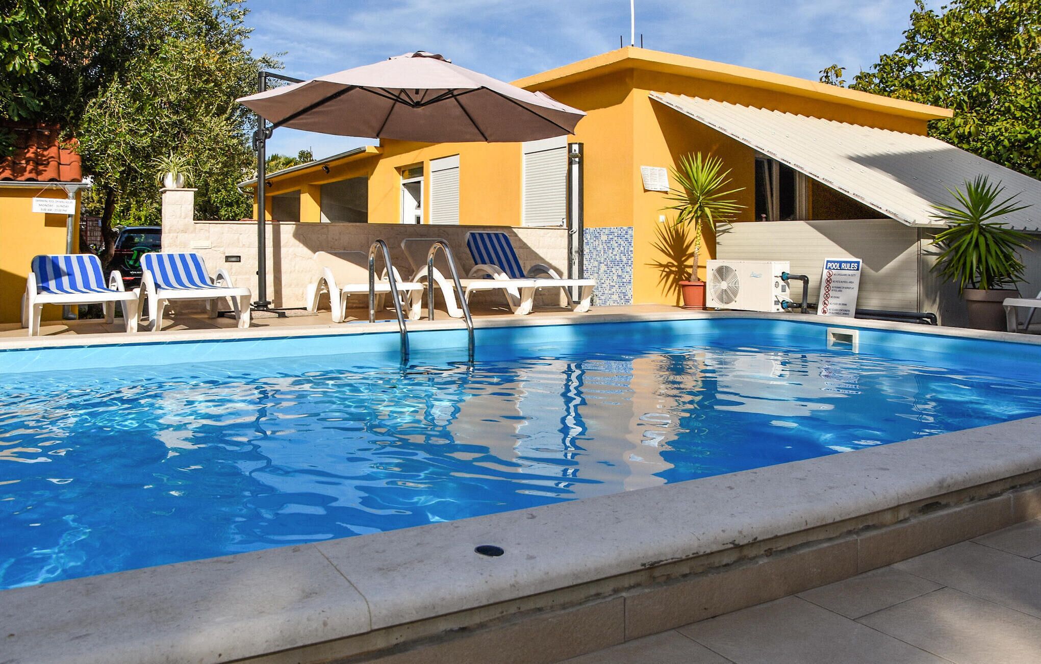 Piscina com espreguiçadeiras e área coberta.
