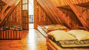 Una habitación con techos altos y suelo de madera, con dos camas y un banco.