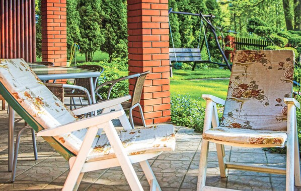 Outdoor seating with metal chairs and a table, surrounded by a brick wall and greenery.