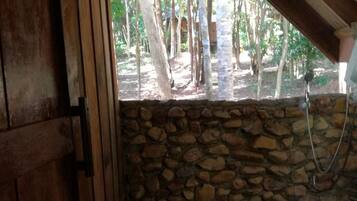 A rustic bathroom with a stone wall, wooden door, and a toilet.