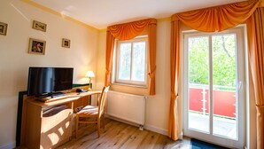 A room with a desk, chair, television, and a window with curtains. - 207 - Hotel Dunenschloss (Karlshagen)