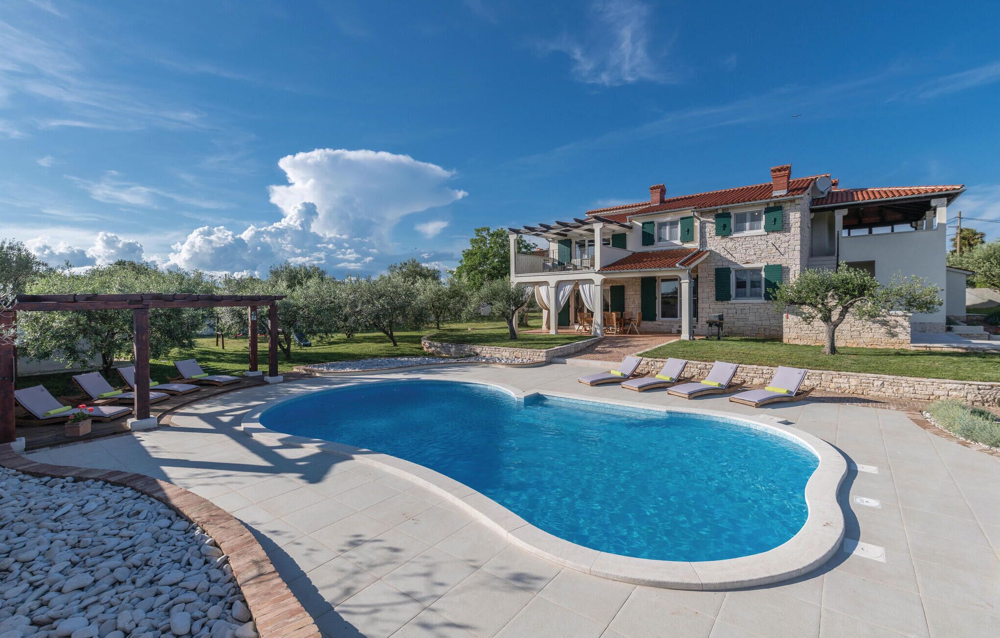 A two-story house with a swimming pool, outdoor seating, and a garden.