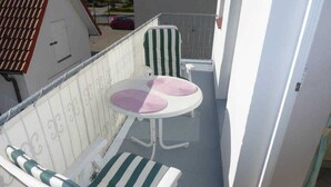 A balcony with a white chair and a small round table with a pink cushion. - (129/3) 2-room apartment - apartment house Plückhahn (Kühlungsborn)