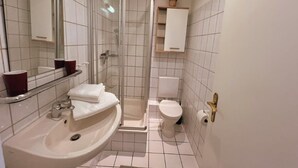 A bathroom with a sink, toilet, shower, and a mirror. - (129/3) 2-room apartment - apartment house Plückhahn (Kühlungsborn)