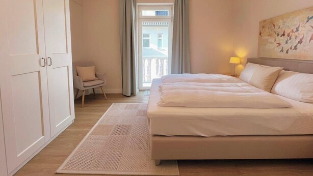 A bedroom with a bed, a chair, a wardrobe, and a painting on the wall. - (129/3) 2-room apartment - apartment house Plückhahn (Kühlungsborn)