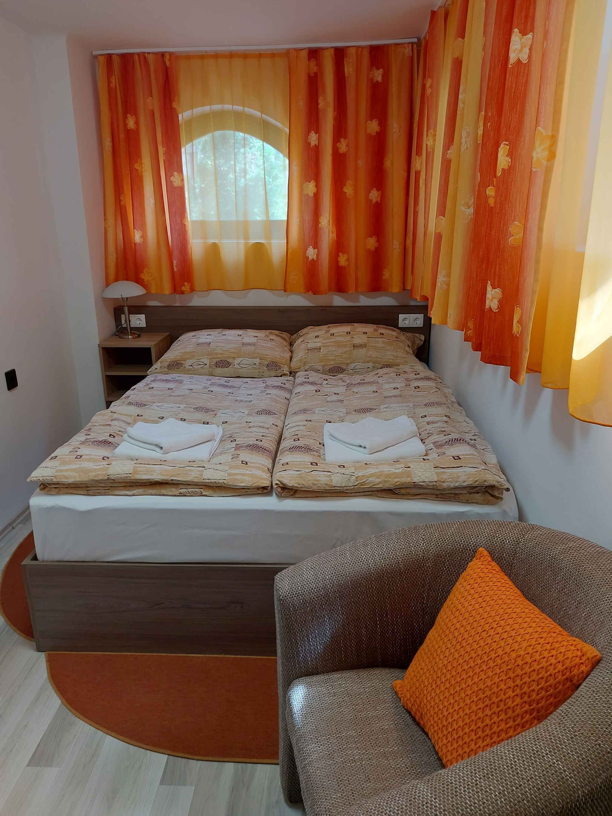 Een slaapkamer met een bed, nachtkastje, lamp en een bank.