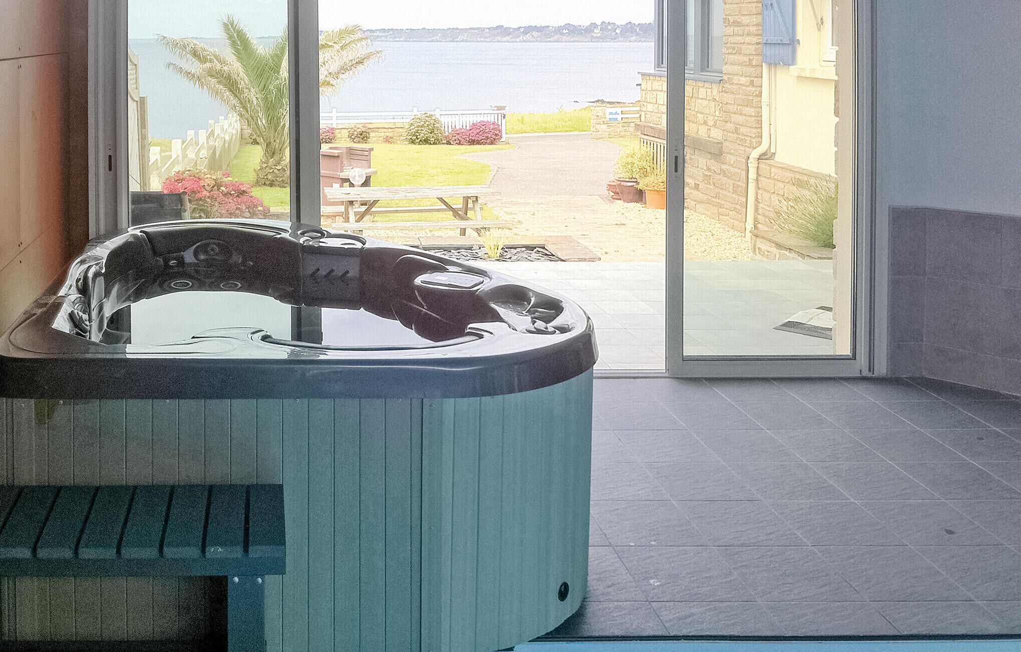 Een bubbelbad in een kamer met uitzicht op een tuin en een waterpartij.