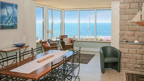 A dining area with a large table, chairs, and a view of the ocean. - Stunning home in Moelan sur Mer (Moelan sur Mer)