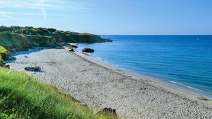 A beach with a rocky shoreline, clear blue water, and grassy cliffs. - Stunning home in Moelan sur Mer (Moelan sur Mer)