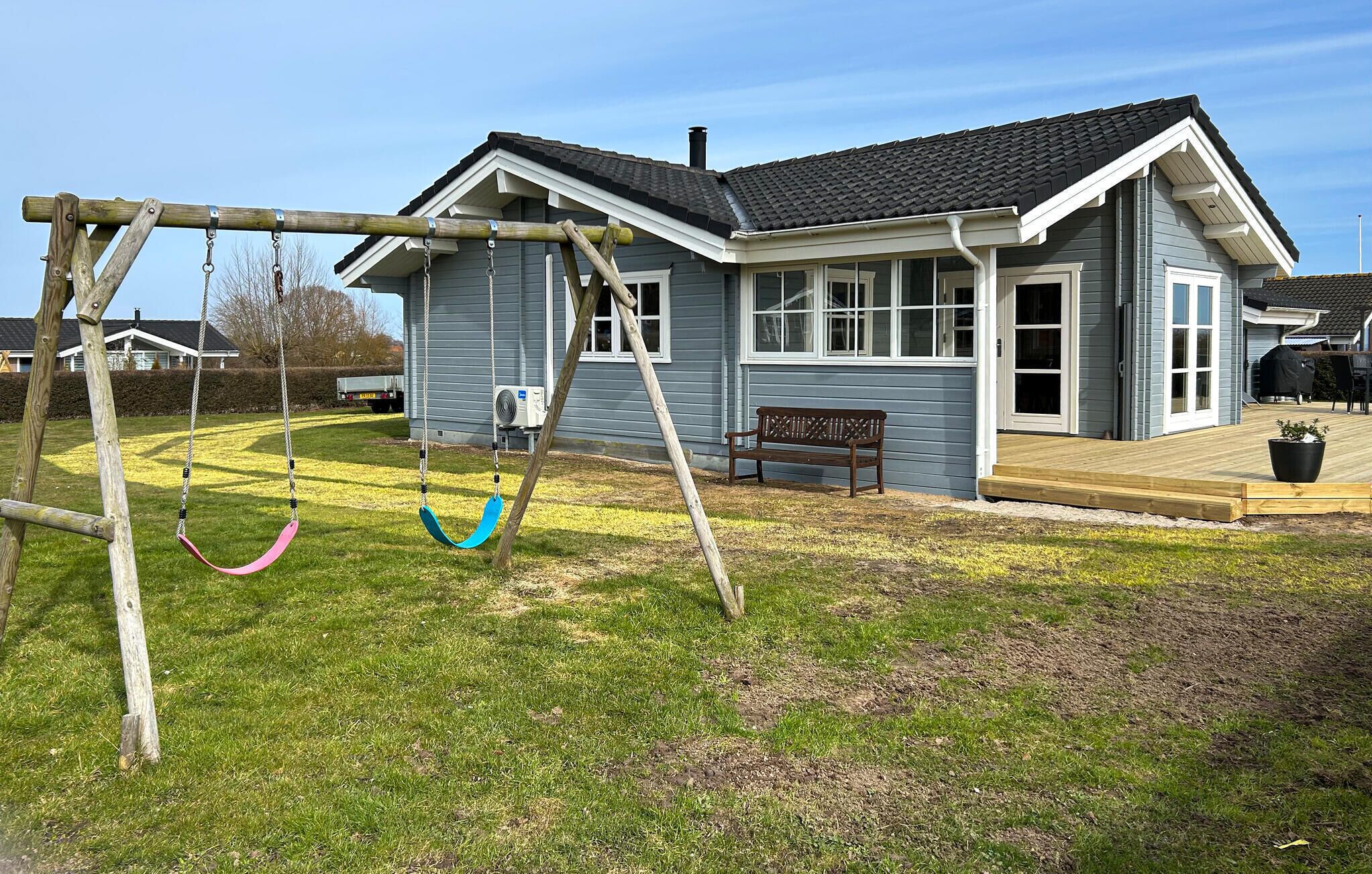 A house with a swing set, a bench, and a covered patio area.