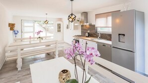 Una cucina moderna con frigorifero integrato, piano cottura e lavello. Si nota una panca e un tavolo con orchidee.