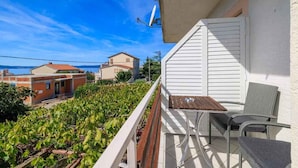 Un balcon avec une table et des chaises, donnant sur un vignoble et des maisons.