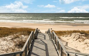 En träpromenad som leder till en strand med utsikt över havet.