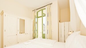 Ein Schlafzimmer mit einem großen Bett, einem Kleiderschrank und einem Fenster mit Vorhängen.