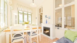 Ein gemütliches Wohnzimmer mit Kamin, einem Essbereich mit Tisch und Stühlen sowie einer Couch mit Kissen.