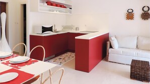 A compact kitchen with a red island, white countertops, and a white dining area with a table set for two. - Lovely apartment in Labin with WiFi (Labin)