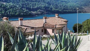 A building with a tiled roof, surrounded by agave plants, overlooking a lake and forested hills. - Lovely apartment in Labin with WiFi (Labin)