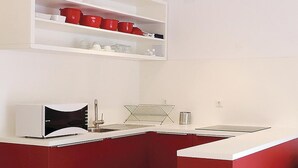 A kitchen with white countertops, a red backsplash, and a white upper shelf with red cups. - Lovely apartment in Labin with WiFi (Labin)